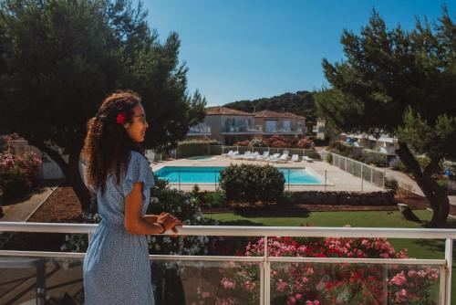 a young girl standing on a fence looking at a garden at Résidence Goélia Les Jardins De Phoebus in Gruissan