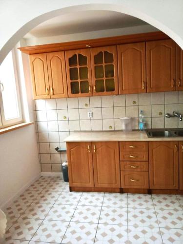 a kitchen with wooden cabinets and a tile floor at Apartament Doris in Ciechocinek