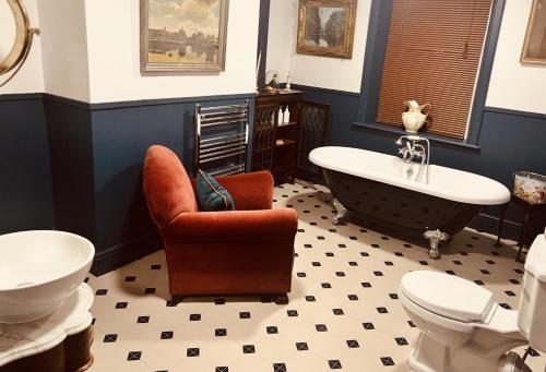 a bathroom with a claw foot tub and a chair and a toilet at The Gin Lounge Rooms in Ilkley