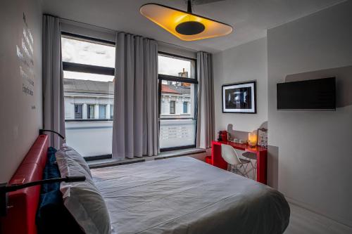 a bedroom with a bed and two windows and a television at Rock Lobster City Lodge in Antwerp