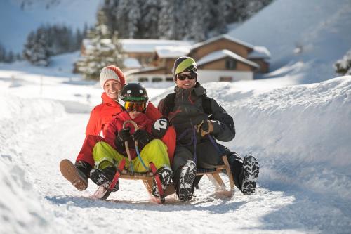 three people sitting on a sled in the snow at Apartments am Bichl in Fulpmes