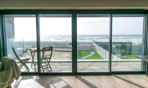 a room with sliding glass doors with a view of the ocean at Edgewater - Bracklesham Bay in Bracklesham Bay