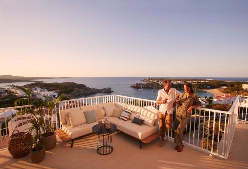 un homme et une femme debout sur un balcon donnant sur l'océan dans l'établissement Palladium Hotel Menorca, à Arenal d'en Castell