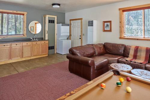 a living room with a leather couch and a pool table at Evergreen Lodge at Yosemite in Groveland