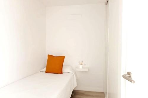 an orange pillow sitting on a white bed in a room at Newly refurbished beachfront apartment. in San Bartolomé de Tirajana