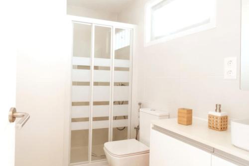a white bathroom with a toilet and a sink at Newly refurbished beachfront apartment. in San Bartolomé de Tirajana