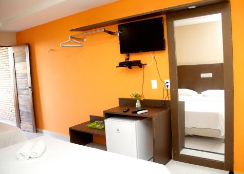 1 dormitorio con 1 cama y TV en la pared en Hotel Costa Atlantico en Areia Branca