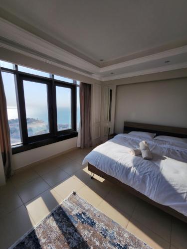 a bedroom with a large bed and large windows at Luxurious 2-bedroom Apartment with Sea View in Doha