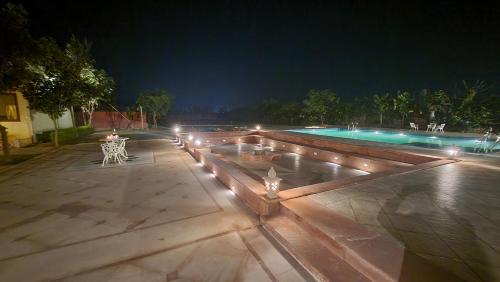 un patio con una piscina con luces por la noche en The Grand Barso (A Luxury Heritage), en Bharatpur