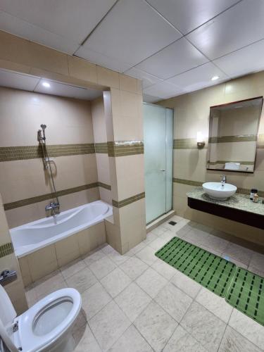 a bathroom with a tub and a toilet and a sink at Luxurious 2-bedroom Apartment with Sea View in Doha