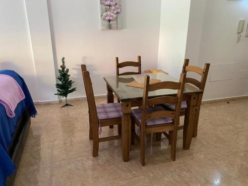 une table à manger avec quatre chaises et un sapin de Noël dans l'établissement JÚPITER EN EDIFICIO REMEDIOS, à Los Llanos de Aridane