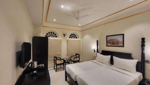 a hotel room with a bed and a table and chairs at The Grand Barso (A Luxury Heritage) in Bharatpur