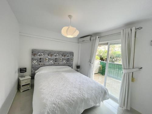 a white bedroom with a bed and a window at Torre Colon in Benidorm