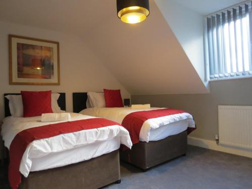 a bedroom with two beds with red and white blankets at Eazy apartments in Newcastle upon Tyne