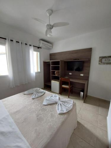 a bedroom with a bed and a dresser and a television at Hotel Casarão Pitangueiras in Guarujá