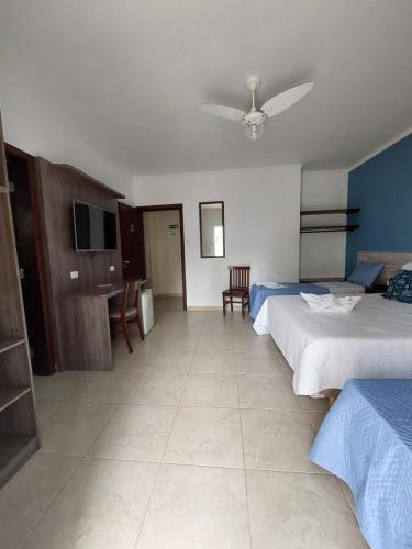 a hotel room with two beds and a flat screen tv at Hotel Casarão Pitangueiras in Guarujá