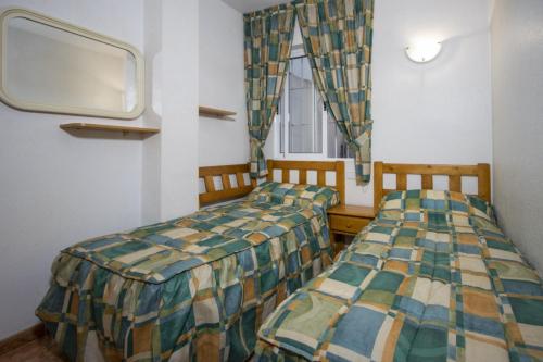 two beds in a room with a window and a tv at Alegria ID40 in Torrevieja
