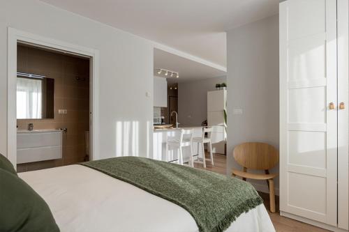 a white bedroom with a bed and a kitchen at El Prau de Mito in Cangas de Onís