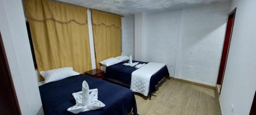 a bedroom with two beds with blue and white sheets at Ashpa Wasi in Salasaca