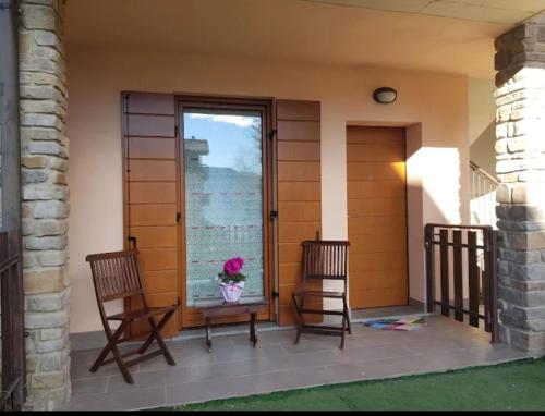 een veranda met 2 stoelen, een tafel en een raam bij Casa Vacanza IL CICLAMINO in Borno