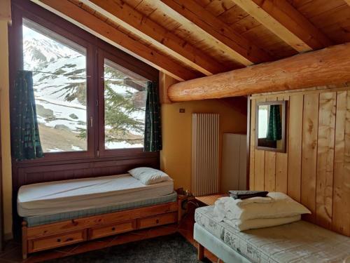 a bedroom with a bed and a window in a cabin at Skichaletcervinia Ski in Ski out 8p op piste nr. 5 uitzicht Matterhorn in Breuil-Cervinia