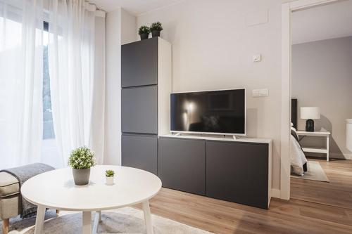 a living room with a tv and a white table at El Prau de Mito in Cangas de Onís