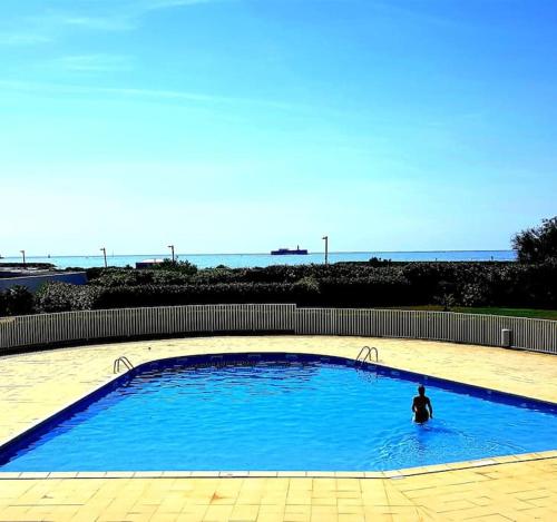 une personne est assise dans une grande piscine bleue dans l'établissement MOM' Blue Paradise Front de Mer 61 m2 CArPe Diem 3 étoilés - 3 Clim, Wifi, lit 160 - 4è Ascenseur Parking, Piscine, Pétanque, Ping-pong - Pistes cyclables, GOLF à 5 mn, au Cap d'Agde