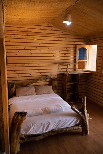 a bedroom with a bed in a log cabin at WaveGo Surf Camp in Imsouane