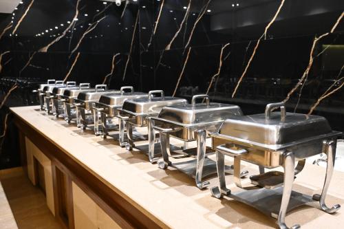 a row of stainless steel pans on a counter at Hotel Lawrence in Amritsar