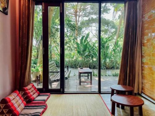 a living room with a couch and a large glass door at River CoCo @ Amphawa in Samut Songkhram