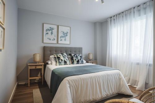 a white bedroom with a bed and a window at El Prau de Mito in Cangas de Onís