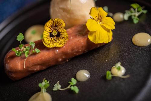 a hot dog on a black plate with flowers on it at No11 Boutique Hotel & Brasserie in Edinburgh
