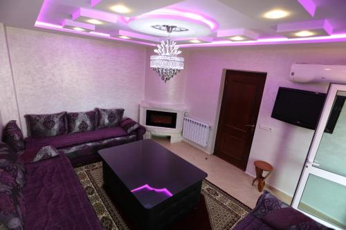 un soggiorno viola con divano e TV di APPARTEMENT AMIRA iFRANE a Ifrane