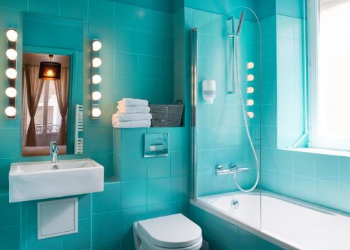 a blue bathroom with a sink toilet and a shower at H&ocirc;tel de Russie in Le Mont-Dore
