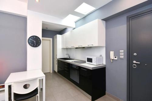 Kuchnia wyposażona jest w białe szafki oraz czarno-białą kuchenkę mikrofalową. w obiekcie Excellent apartment luxuriously renovated w mieście Larisa