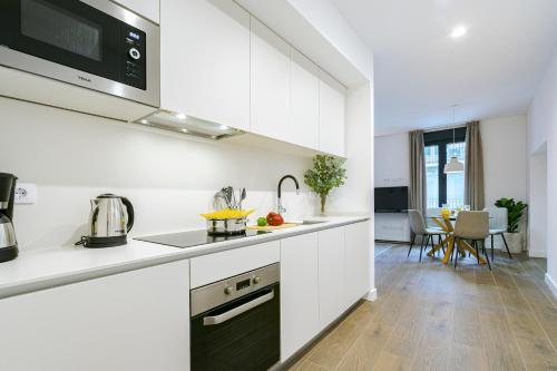 cocina con armarios blancos y encimera en Feelathome Castilla Apartments, en Madrid