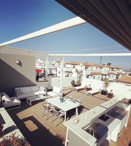 a rooftop deck with white furniture and a view of the ocean at Chipibeach B&B, Hostal Boutique in Chipiona