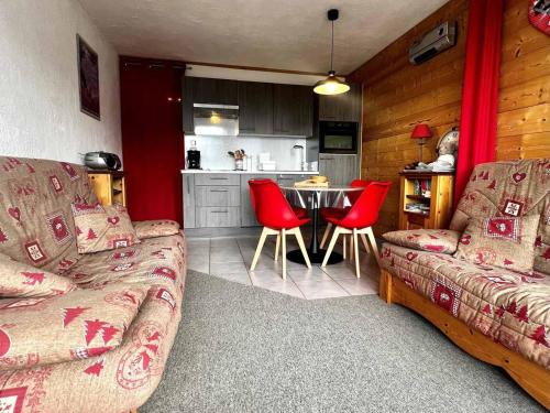- un salon avec un canapé et une table avec des chaises rouges dans l'établissement Studio pieds des pistes avec piscine extérieure - FR-1-505-51, à Notre-Dame-de-Bellecombe
