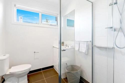 y baño blanco con aseo y ducha. en 2Bdrm Beachside Town House with Ocean Views en Seaford