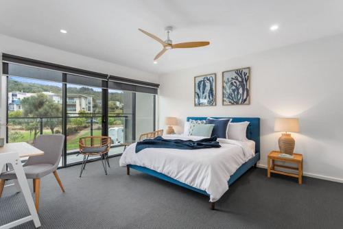 1 dormitorio con 1 cama azul, mesa y sillas en Modern Spacious Coastal 4 Bedroom Town House, en Safety Beach