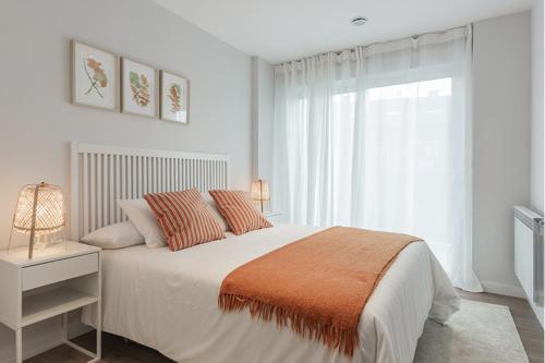a white bedroom with a large bed and a window at El Prau de Mito in Cangas de Onís