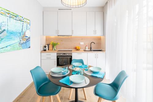cocina con mesa de comedor y sillas azules en Aranygesztenye Apartmanház, en Balatonudvari