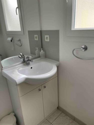 une salle de bain blanche avec un lavabo et un miroir dans l'établissement Appartement et cour St Jean de Monts +parking, à Saint-Jean-de-Monts
