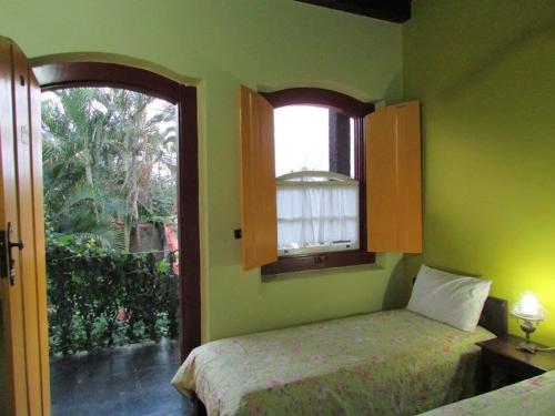 a green bedroom with two beds and a window at Pousada Solar do Algarve em Paraty há 5 minutos do Centro Histórico in Paraty