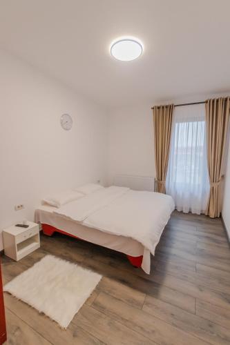 a white bedroom with a bed and a window at Penthouse Luxury Falticeni in Fălticeni