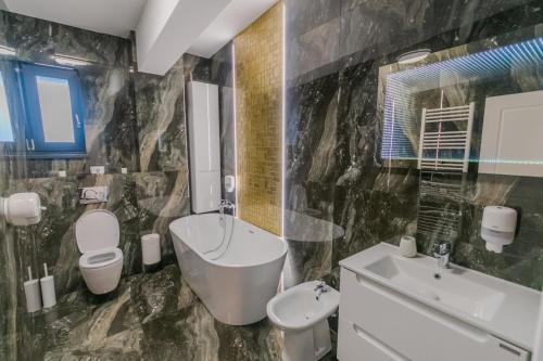 弗爾蒂錢尼的住宿－Penthouse Luxury Falticeni，浴室配有盥洗盆、卫生间和浴缸。