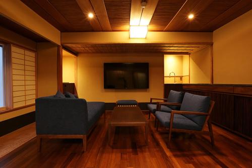 a living room with chairs and a flat screen tv at Monjusou Shourotei in Miyazu