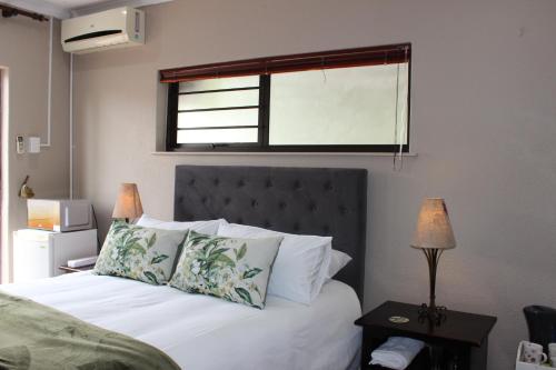 a bedroom with a bed with white sheets and a window at Amru Guesthouse B&B in Brackenfell