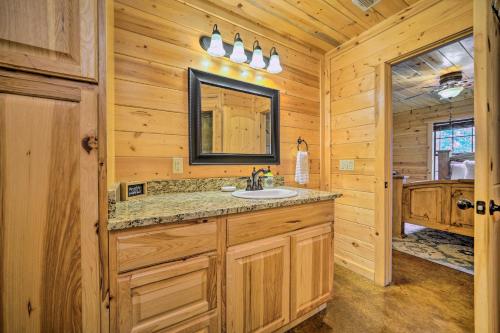 uma casa de banho em madeira com um lavatório e um espelho. em Cabin with Games and Hot Tub, 4 Mi to Beavers Bend! em Broken Bow