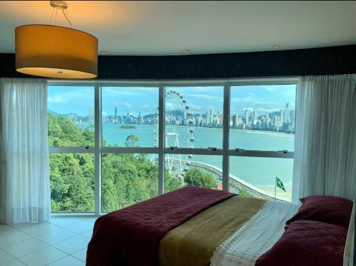 a bedroom with a large window with a view of the city at Lindo Apto no Terraços da Rainha in Balneário Camboriú